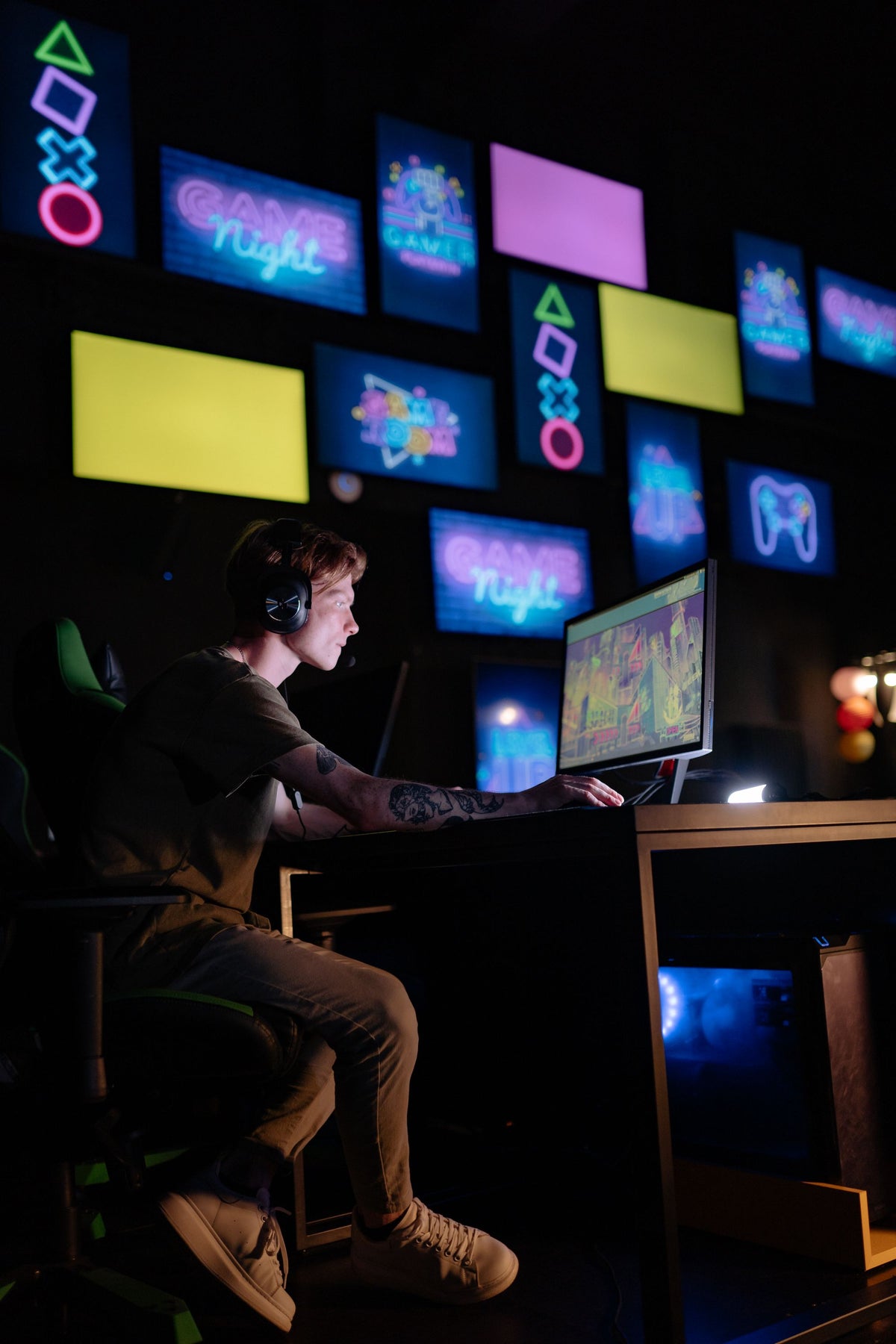 Young gamer focused at a neon-lit multi-screen setup